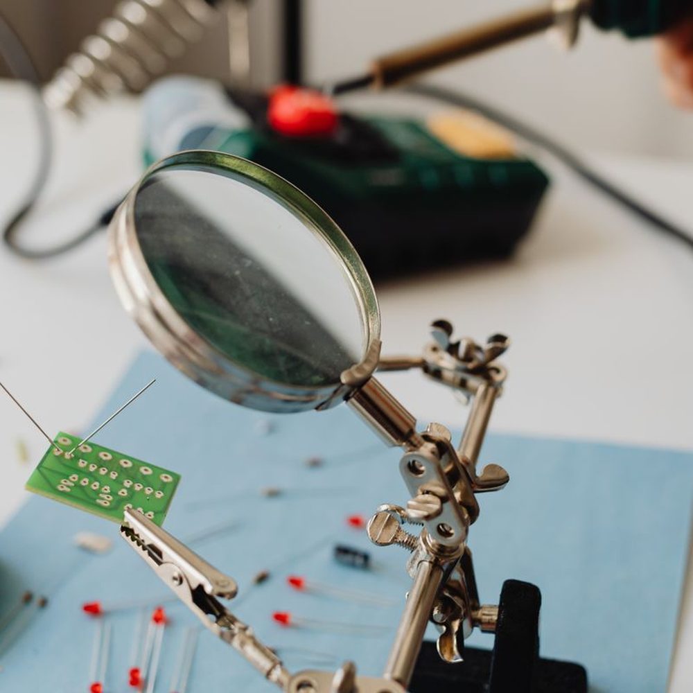 A small circuit board examined under a magnifying glass