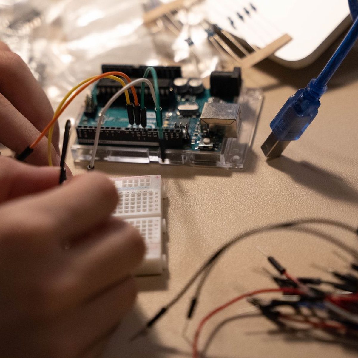 Hands connecting wires to a microcontroller board