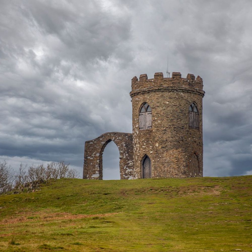 A stone folly tower standing alone on a hillside